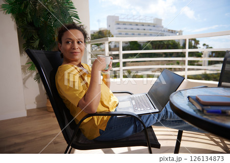 Woman Relaxing Outdoors With Coffee and Laptop on a Balcony Woman Relaxing Outdoors With Coffee and Laptop on a Balcony 126134873