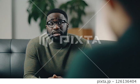 African American man in eyeglasses at an appointment with a psychologist. He delves into the problem and helps the patient solve it. Psychotherapist listens carefully to the patient’s story. African American man in eyeglasses at an appointment with a psychologist. He delves into the problem and helps the patient solve it. Psychotherapist listens carefully to the patient’s story. 126136404