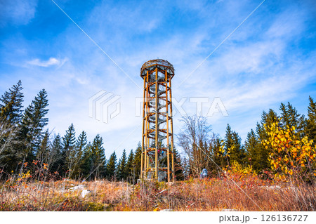 Svetly vrch lookout tower stands tall amidst vibrant autumn foliage in Albrechtice. The clear sky highlights the scenic beauty of the surrounding Jizera Mountains. 126136727