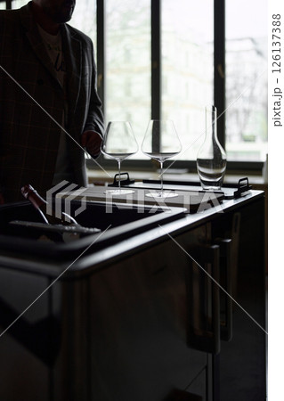 Clean wine glasses and decanter are on the table of a special wine cabinet, stylish table setting, ice, light from window, decoder and degasser 126137388