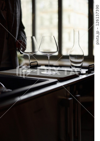 Clean wine glasses and decanter are on the table of a special wine cabinet, stylish table setting, ice, light from window, decoder and degasser 126137390