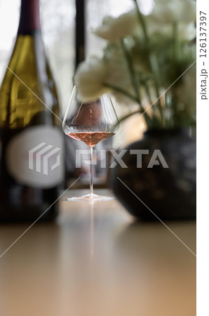 Bottle of rose champagne and wine glass is on table in the restaurant, flowers, wine cabinet, sparkling wine Bottle of rose champagne and wine glass is on table in the restaurant, flowers, wine cabinet, sparkling wine 126137397