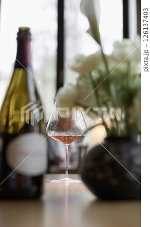 Bottle of rose champagne and wine glass is on table in the restaurant, flowers, wine cabinet, sparkling wine 126137403