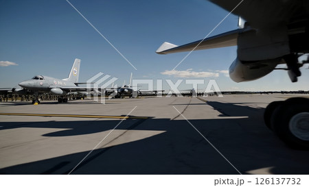 Powerful military aircraft taxiing across airfield, generating dust clouds while ground crew standing precisely in uniform formation with strategic operational readiness 126137732