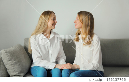 Happy smiling women talking, mature mother and adult daughter together sitting on couch at home 126137766
