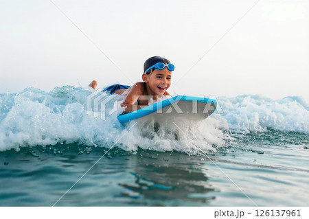 Young Boy Enjoying Bodyboarding in the Ocean on a Sunny Day During Summer Young Boy Enjoying Bodyboarding in the Ocean on a Sunny Day During Summer 126137961