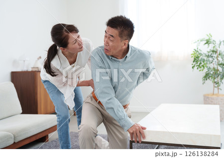 ぎっくり腰のシニア男性とサポートするシニア女性 126138284