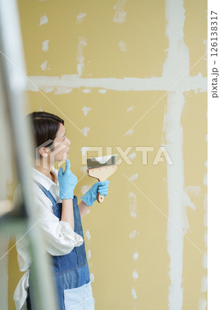 石膏ボードにパテを塗るDIYする女性 126138317