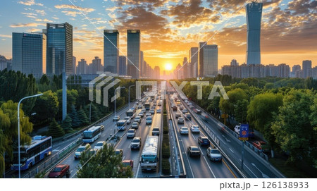 The bustling highway is filled with vehicles, with the city skyline rising behind them and the sun setting over the buildings. 126138933