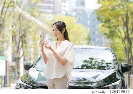 車の前でスマホを操作する若い女性 車の前でスマホを操作する若い女性 126139689