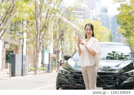 車の前でスマホを操作する若い女性 車の前でスマホを操作する若い女性 126139695