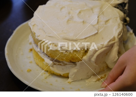 手作りスポンジケーキに生クリームを塗る子供の手元 126140600