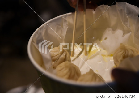 Close-up of steamed Chinese dumplings with crab and pork in a take-out bowl on Yuyuan Old Street, ready to eat with chopsticks in Shanghai, China Close-up of steamed Chinese dumplings with crab and pork in a take-out bowl on Yuyuan Old Street, ready to eat with chopsticks in Shanghai, China 126140734