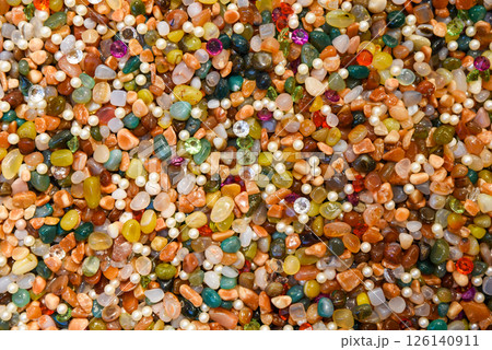 Colorful background of assorted polished gemstones, pearls, and crystals. Bright, vibrant texture of mixed natural stones and beads in various shapes and colors, ideal for abstract backdrop 126140911