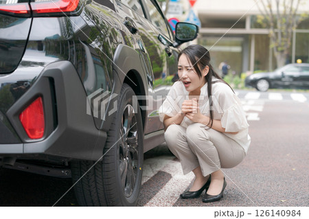 タイヤのトラブルを確認する若い女性 タイヤのトラブルを確認する若い女性 126140984