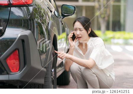 タイヤのトラブルを確認する若い女性 126141251