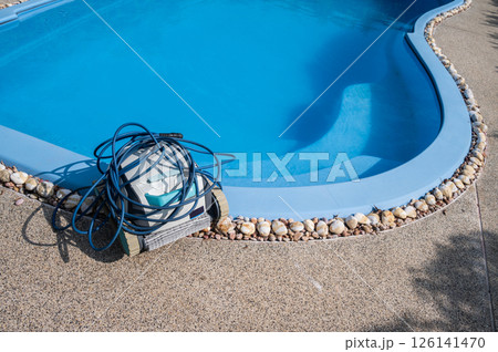 A Robotic pool cleaner preparation at the poolside before using it. Robotic is solutions for swimming pool care, deep clean pool surfaces, removing leaves for you. 126141470