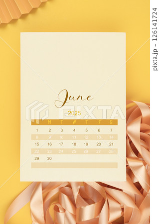 June 2025 calendar page with ribbon on yellow background. June 2025 calendar page with ribbon on yellow background. 126141724