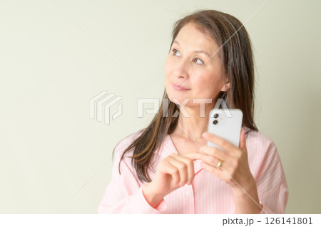 スマホを手にして考え中のシニア女性 スマホを手にして考え中のシニア女性 126141801