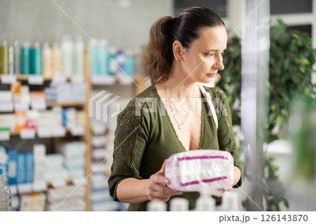 Middle-aged woman choosing feminine pads in chemistry Middle-aged woman choosing feminine pads in chemistry 126143870