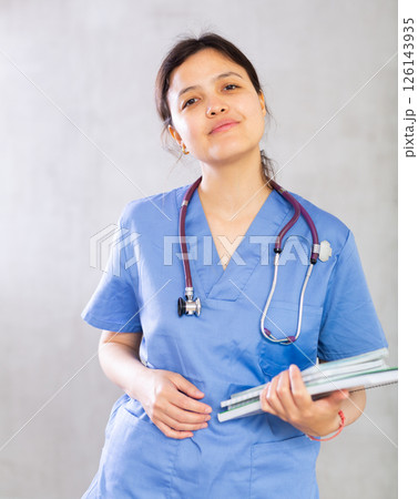 Positive young woman doctor holding medical records Positive young woman doctor holding medical records 126143935