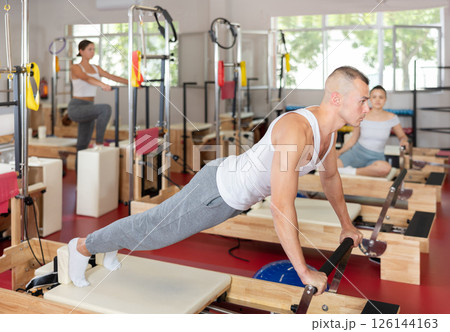 Young man training his abs on pilates reformer 126144163