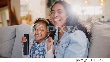 Mom, girl and happy for watching tv on couch with remote control for movie, hug or bonding with love. Child, mother and daughter with smile, care or laugh on sofa for streaming film in family home 126144209