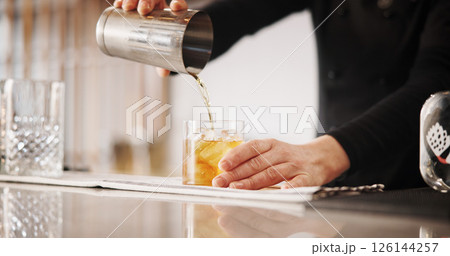 Cocktail, mixology and hands of barman with whiskey glass, ice and tools for artisan beverage recipe. Cafe, small business pub and person at counter with happy hour drinks, process and craft alcohol Cocktail, mixology and hands of barman with whiskey glass, ice and tools for artisan beverage recipe. Cafe, small business pub and person at counter with happy hour drinks, process and craft alcohol 126144257