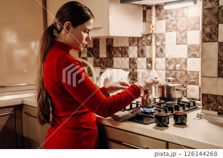 Woman Cooking Kitchen Evening Dinner: Home cooking preparation, nighttime kitchen scene. 126144268