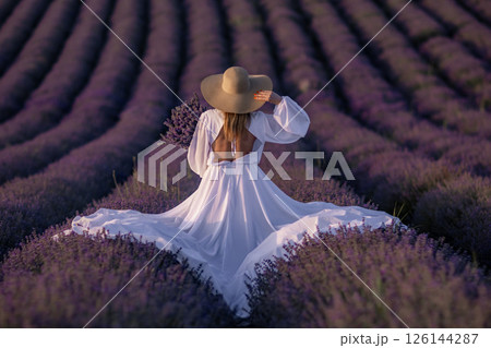 Lavender Fields Provence Woman; Sunset photoshoot: Elegant woman in white dress enjoys picturesque Provence lavender fields during golden hour. 126144287