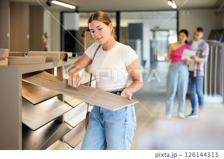 Young woman choosing laminate flooring in store Young woman choosing laminate flooring in store 126144313