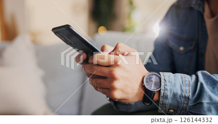 Phone, hands and man on sofa in home for networking, social media or online communication. Closeup, cellphone and male person chatting on dating app for contact or connection in living room at house. 126144332