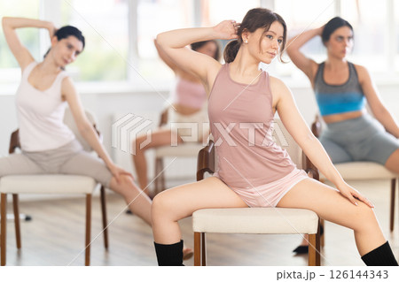 Young female dancer practicing lap dance on chair in studio 126144343