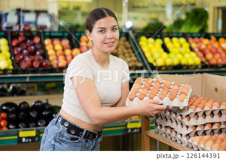 Young lady in supermarket buys chicken eggs. Young lady in supermarket buys chicken eggs. 126144391
