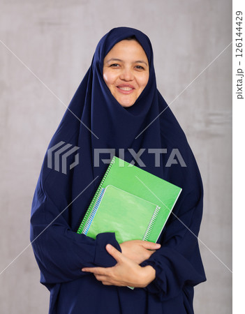 Portrait of young woman student in a khimara with notebooks in hands 126144429