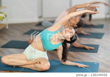 Young girl teaches yoga lesson, shows students technique of performing padmasana asana 126144456