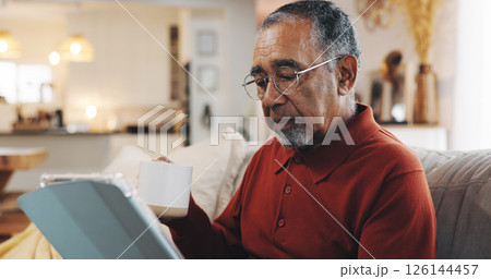 Coffee, tablet and senior man with living room, sofa and reading online news blog post. Relax, digital technology and mature person drinking a latte and scroll internet and social media at home 126144457