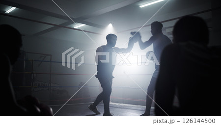 Learning, team and health with men in boxing ring for sparring practice, boxer training and fitness coaching. Mma club, sports and martial arts fighter with people in gym for personal trainer Learning, team and health with men in boxing ring for sparring practice, boxer training and fitness coaching. Mma club, sports and martial arts fighter with people in gym for personal trainer 126144500