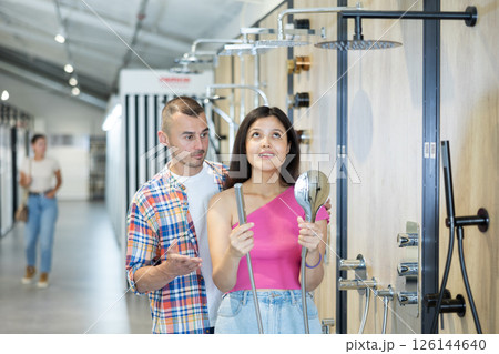 Interracial couple discussing selection of showerhead in plumbing supply store 126144640