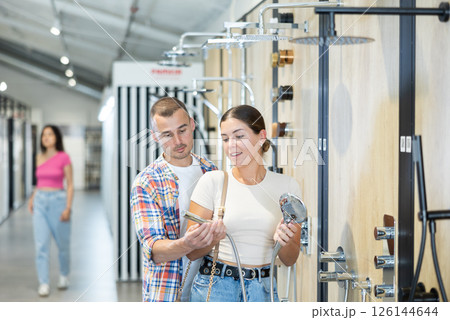 Interested couple choosing showerheads in plumbing supply store Interested couple choosing showerheads in plumbing supply store 126144644