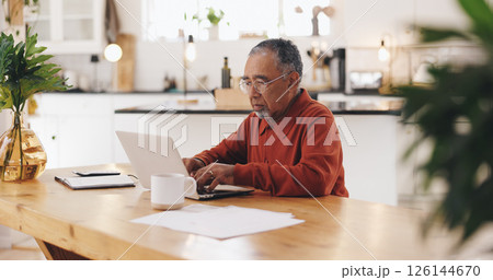 Senior man, laptop and taxes in kitchen with typing, documents and financial review for pension. Elderly person, computer and paperwork with budget, will and planning for retirement income in home 126144670