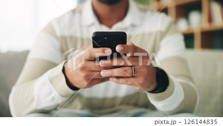 Man, hands and relax with phone on sofa for app download, playing online game or streaming subscription. Closeup, scroll or person with smartphone in home for social media, dating site or mobile chat 126144835