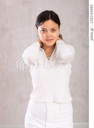 Portrait of an attractive young asian girl in a white trouser suit on gray background 126144995