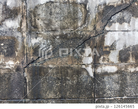 A cracked concrete wall shows signs of age and neglect, creating somber and deteriorating atmosphere. wall, crack, and concrete are visible A cracked concrete wall shows signs of age and neglect, creating somber and deteriorating atmosphere. wall, crack, and concrete are visible 126145665