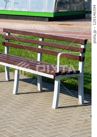 A wooden park bench with elegant white legs and comfortable arms A wooden park bench with elegant white legs and comfortable arms 126146394