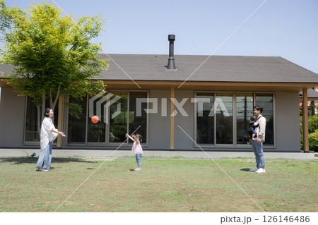 平屋の戸建ての庭の前でボールを投げて遊ぶ家族と子供の幸せの不動産のファミリーイメージ 126146486