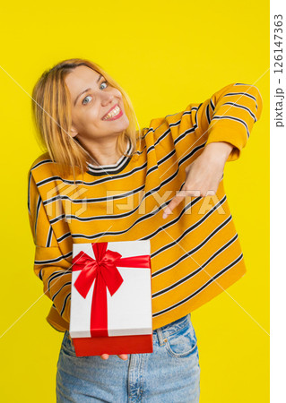 Smiling woman presenting birthday gift present box stretches out hands, promotion discount sale 126147363