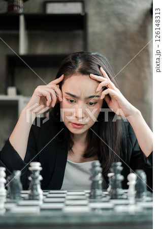 A woman deeply focused on a chess game, contemplating her next move in a modern interior setting. A woman deeply focused on a chess game, contemplating her next move in a modern interior setting. 126148313