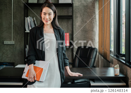 Professional woman in a stylish office setting, exuding confidence and success, holding documents. Professional woman in a stylish office setting, exuding confidence and success, holding documents. 126148314