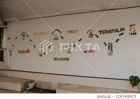 Vibrant multilingual welcome wall mural with international greetings and travel icons at Lisbon train station interior colorful artistic decoration for cultural diversity. High quality photo 126148425
